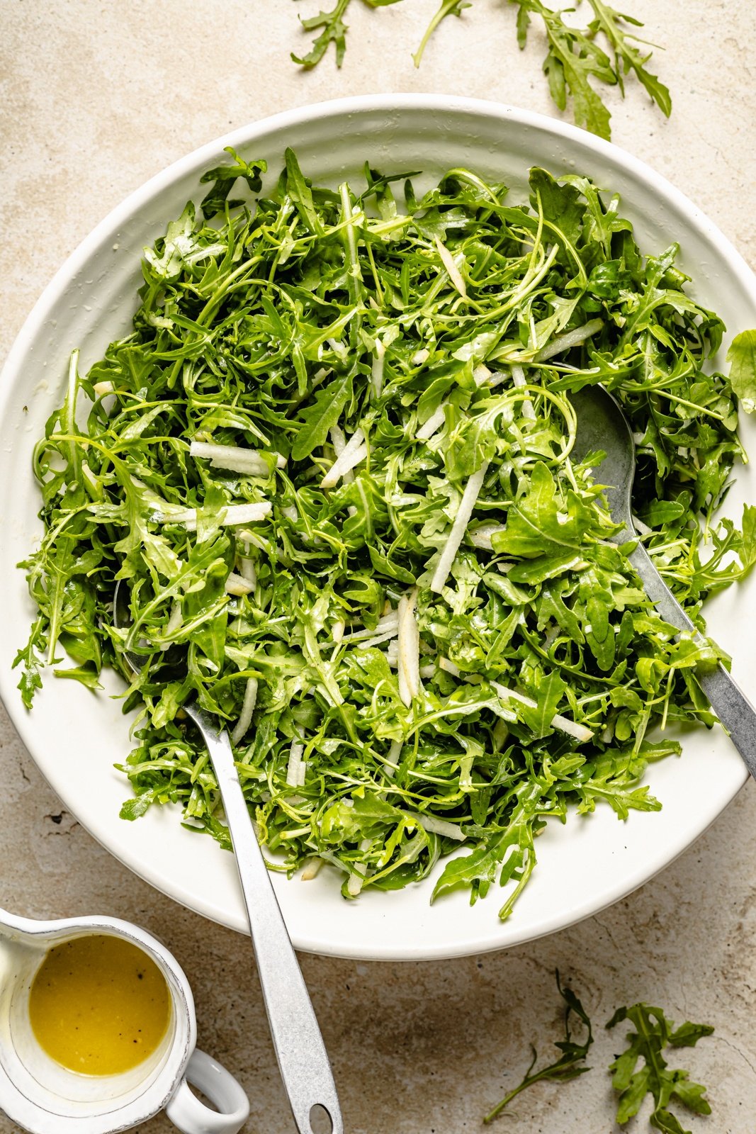 tossing a pear arugula salad in a bowl