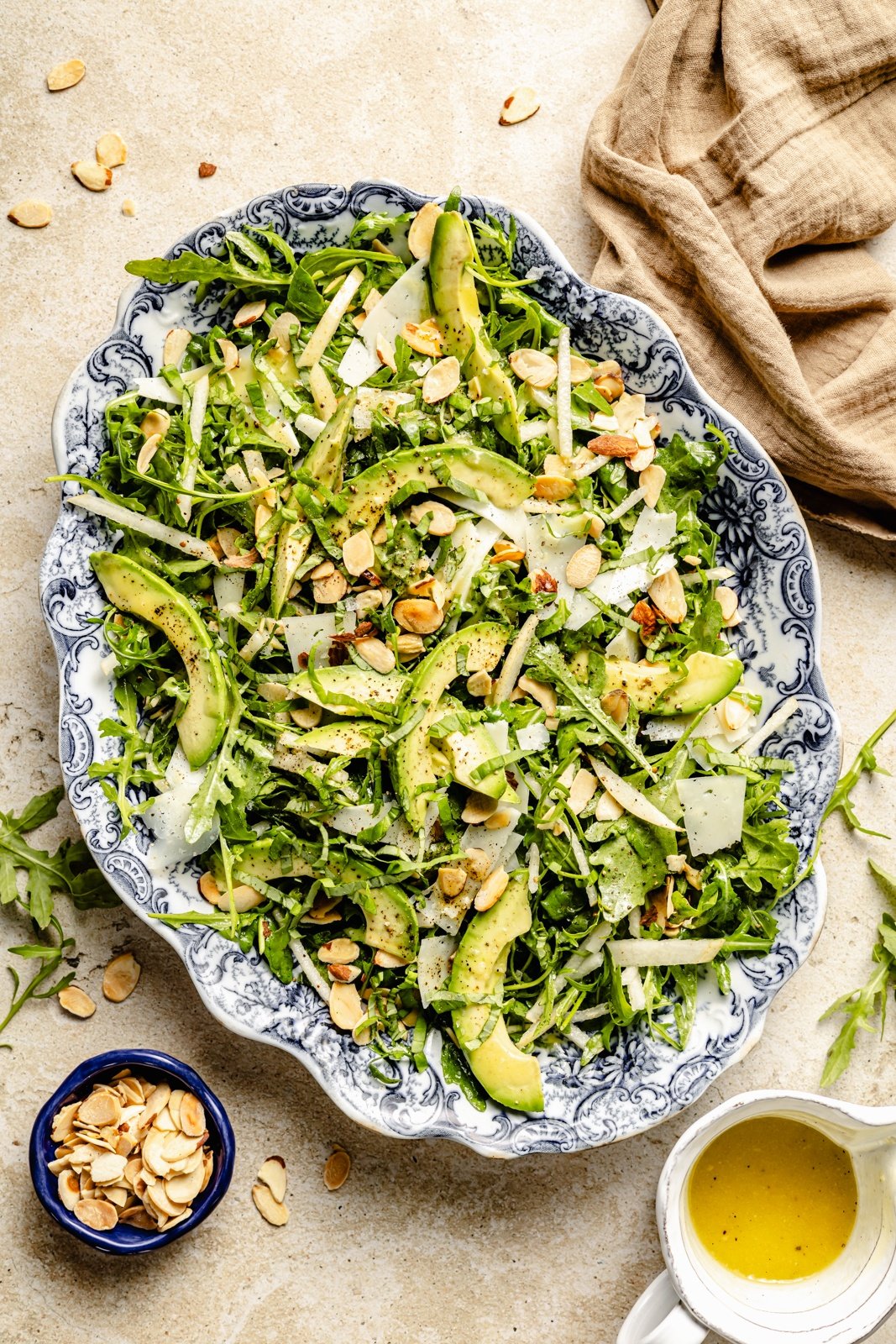 simple arugula pear salad with asiago cheese and avocado on a platter