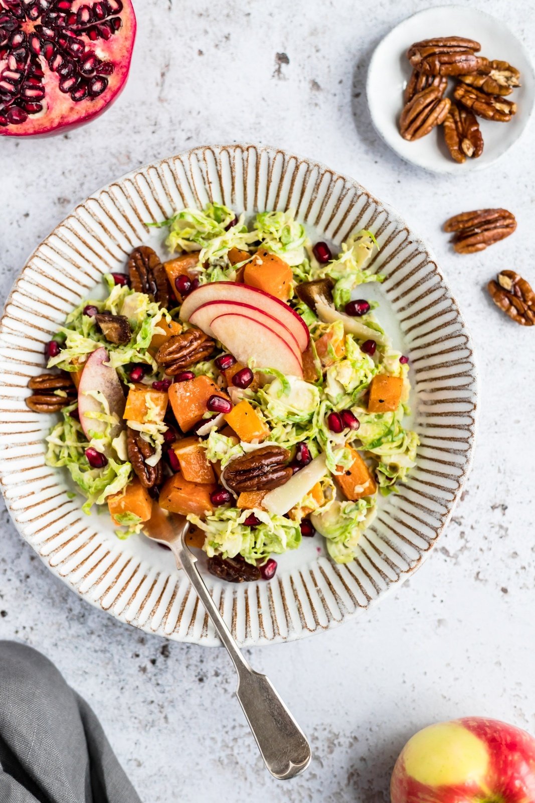 brussels sprouts caesar salad with apples and butternut squash on a plate