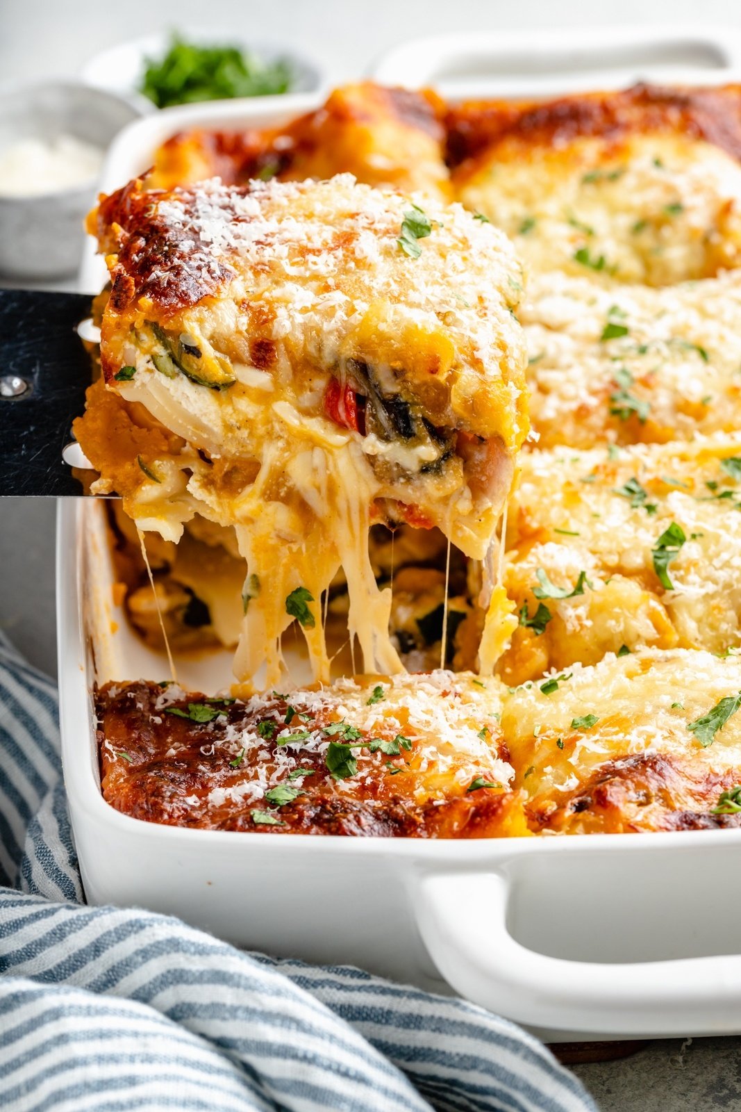lifting a slice of butternut squash lasagna out of a pan