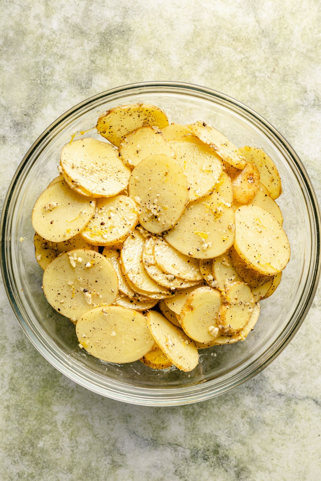 tossing sliced potatoes in butter and herbs to make stacked potatoes
