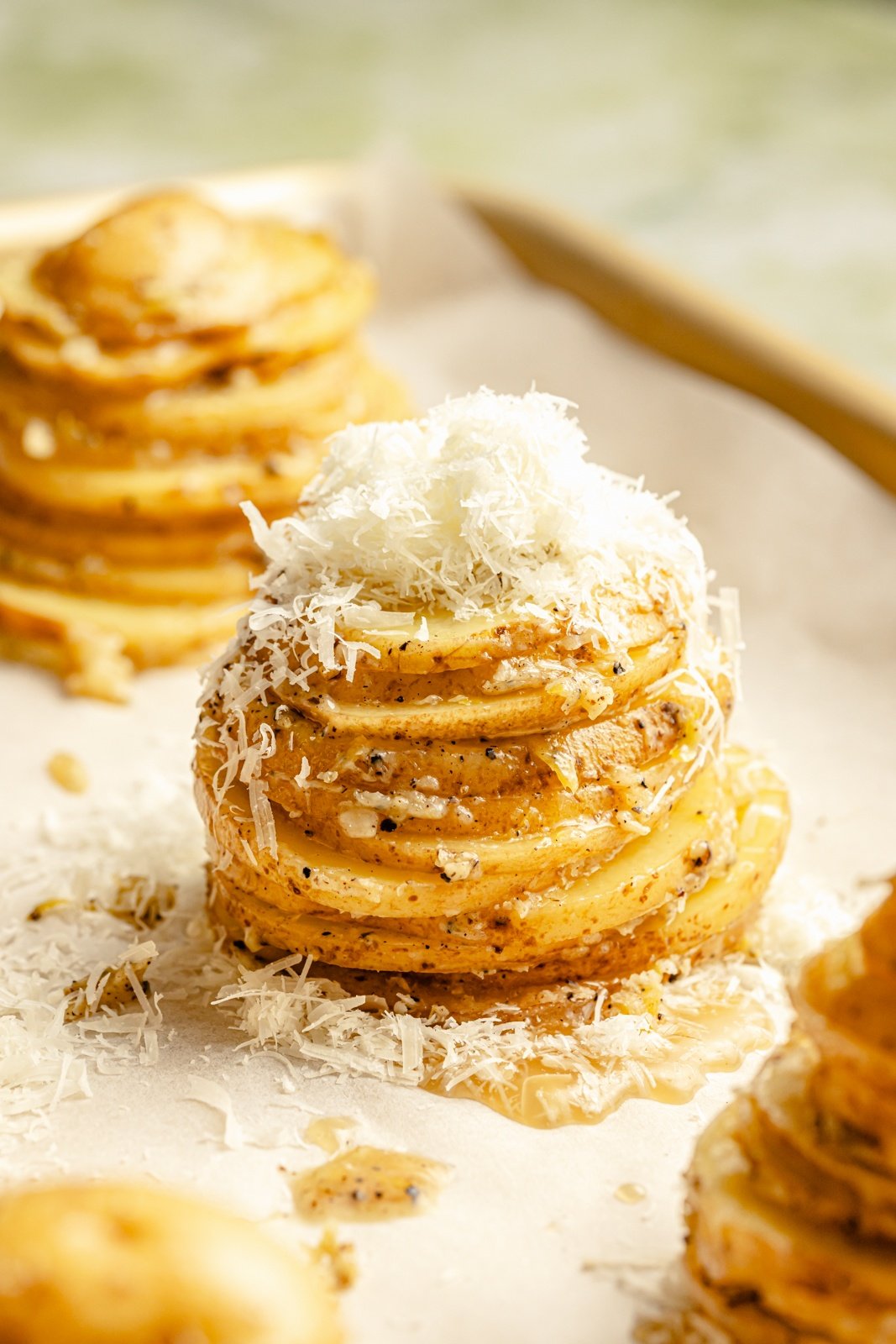 unbaked potato stacks topped with cheese on a baking sheet