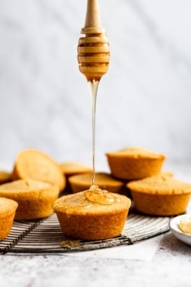 drizzling honey on a gluten free cornbread muffin