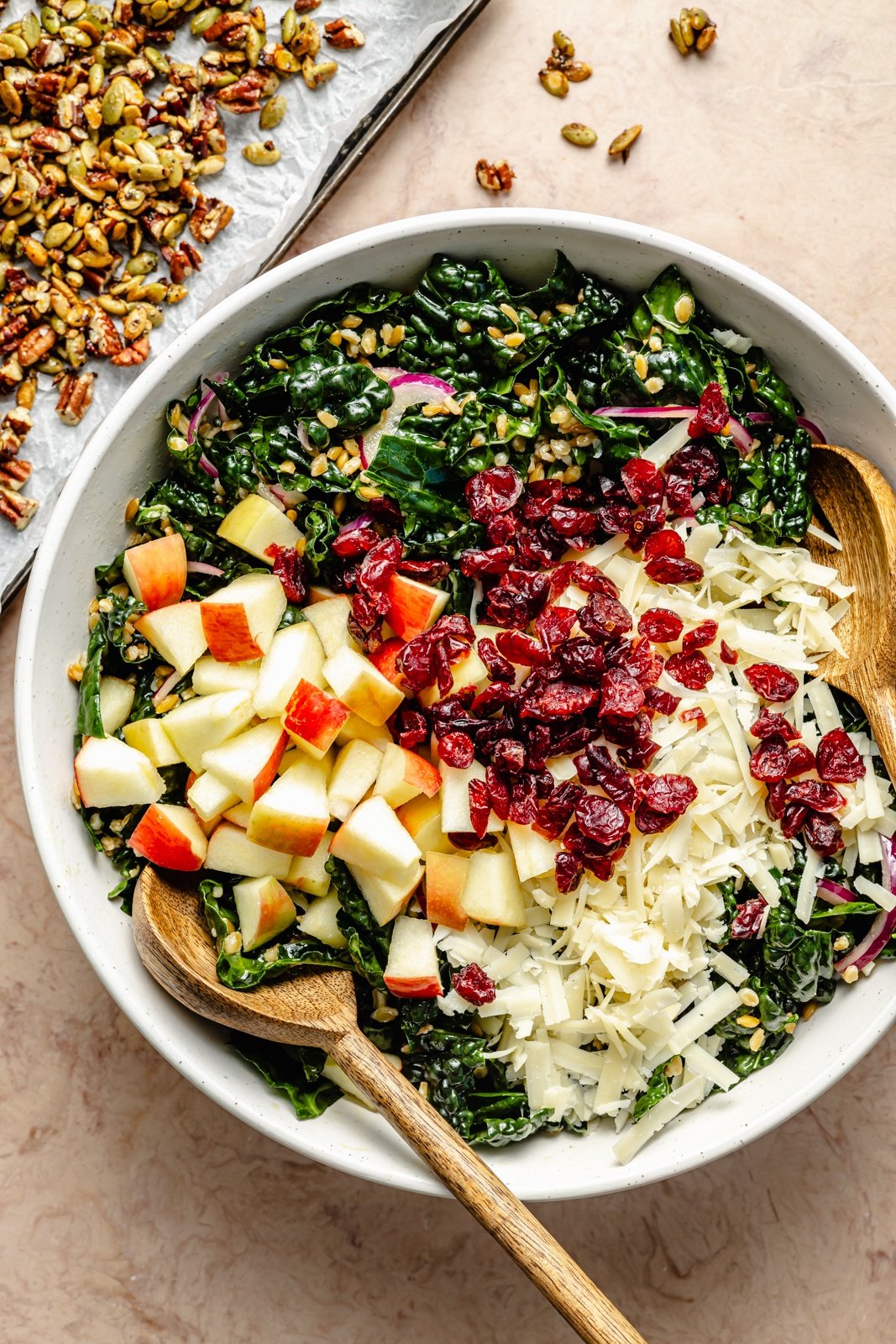 tossing an apple kale farro salad in a bowl