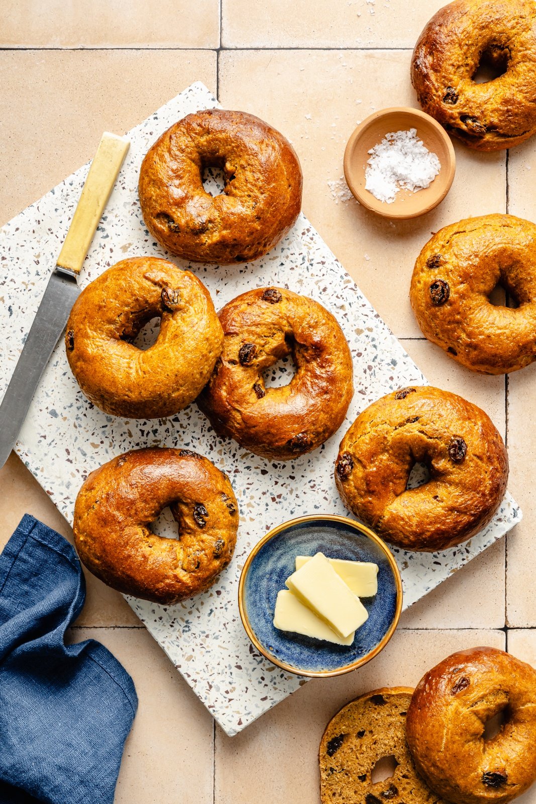 high protein pumpkin bagels on a board next to dishes of butter and salt