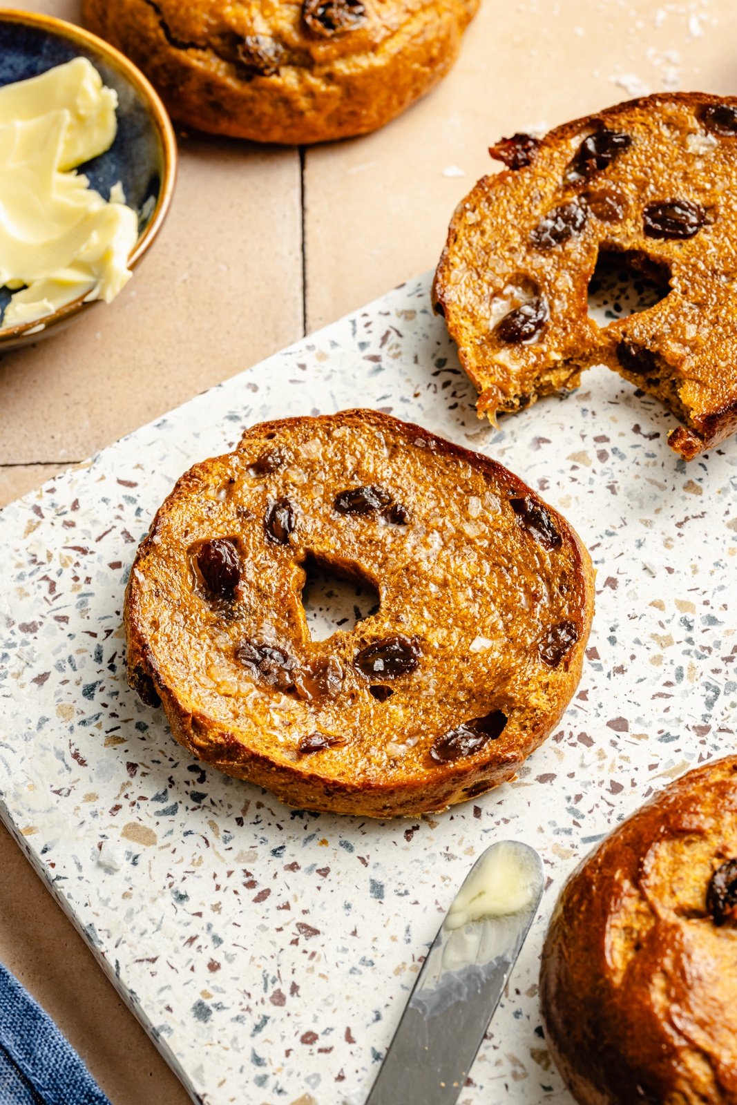 half of a protein pumpkin bagel with raisins on a board