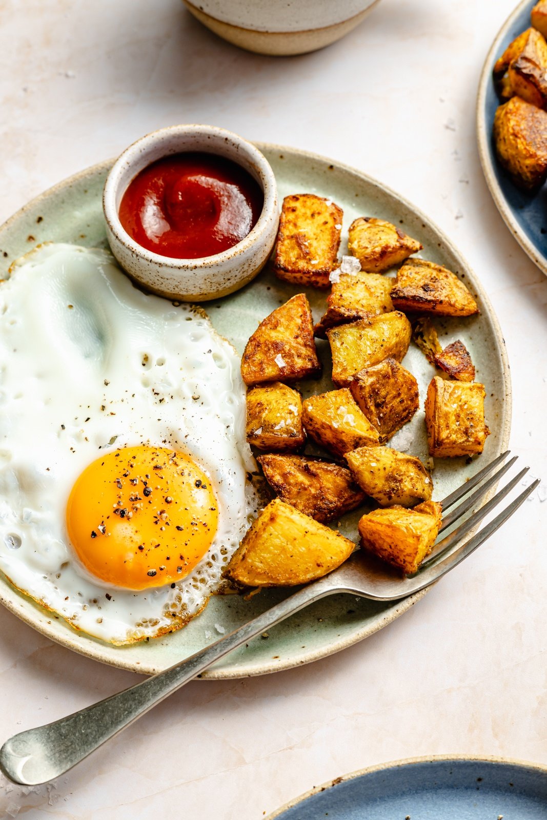 breakfast potatoes, an egg, and ketchup on a plate