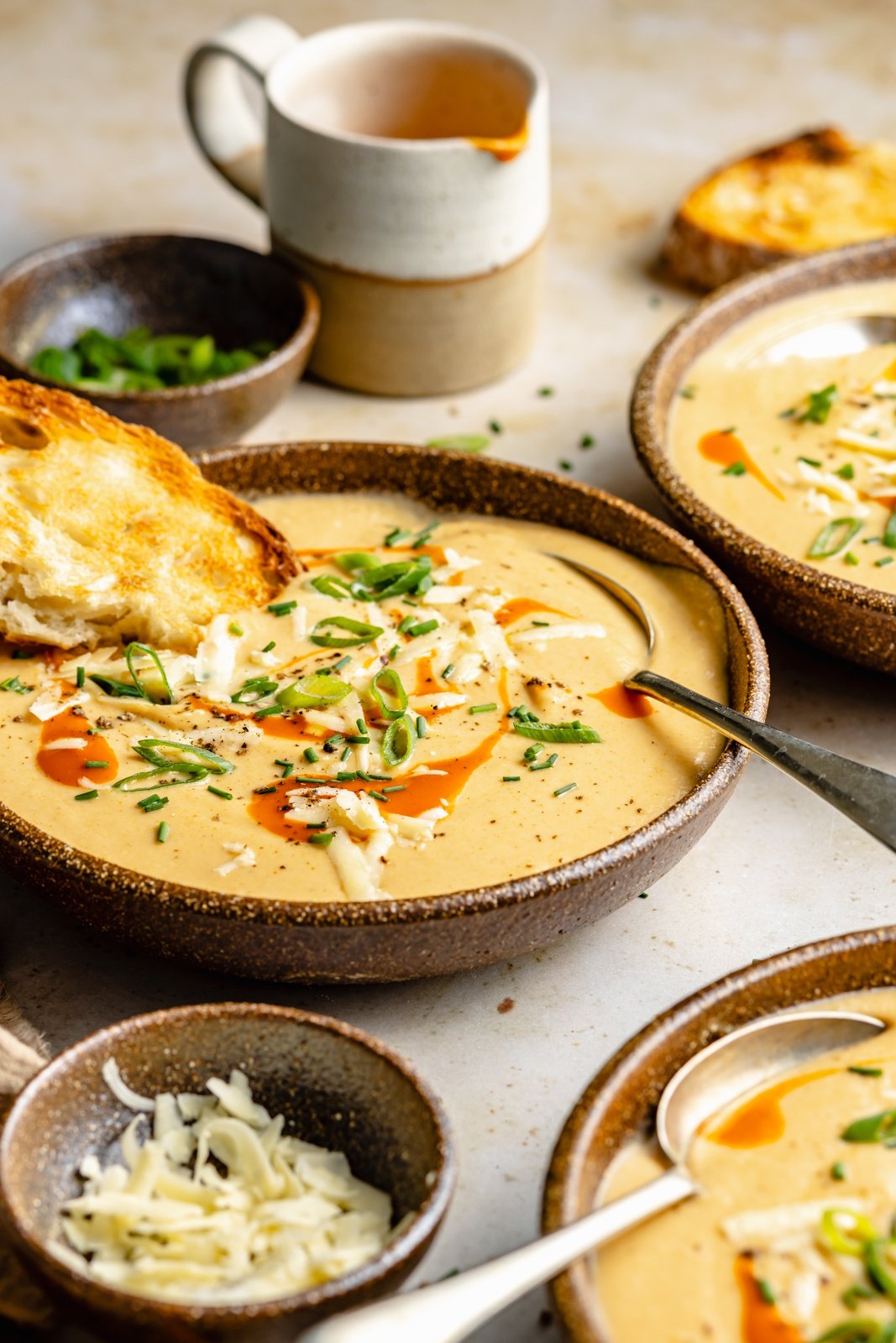 buffalo roasted cauliflower soup in a bowl with a piece of toasted bread