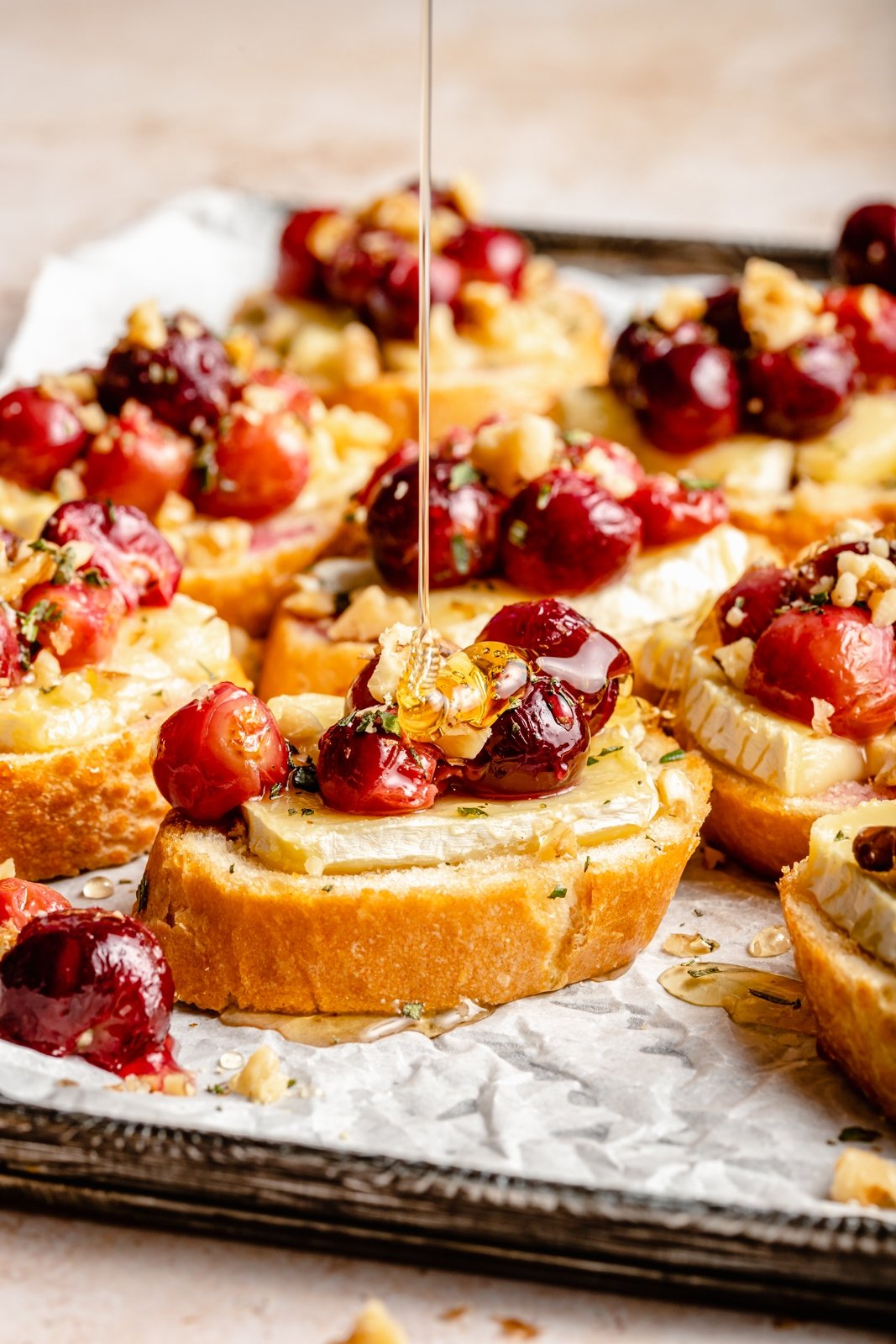 drizzling honey on a roasted grape and brie crostini