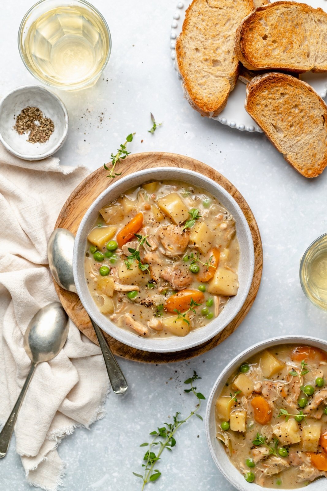 slow cooker white wine chicken stew in two bowls next to bread slices