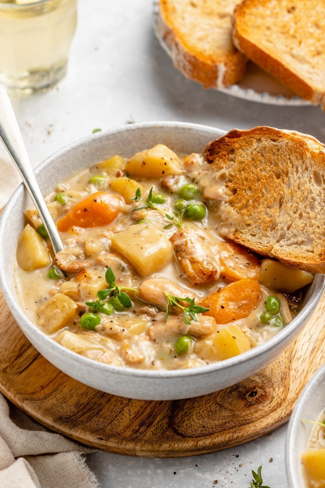 slow cooker white wine chicken stew in a bowl with a piece of bread