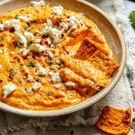 red pepper feta dip in a bowl with pita crackers