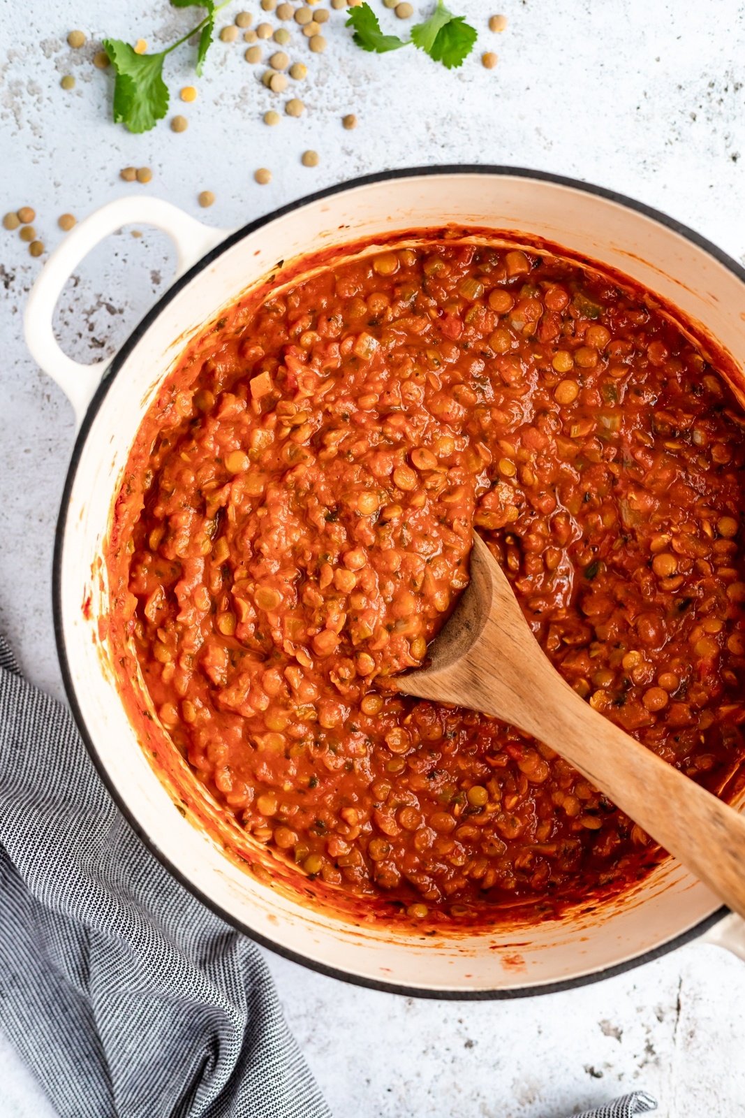 vegan tomato lentil soup in a pot with a wooden spoon