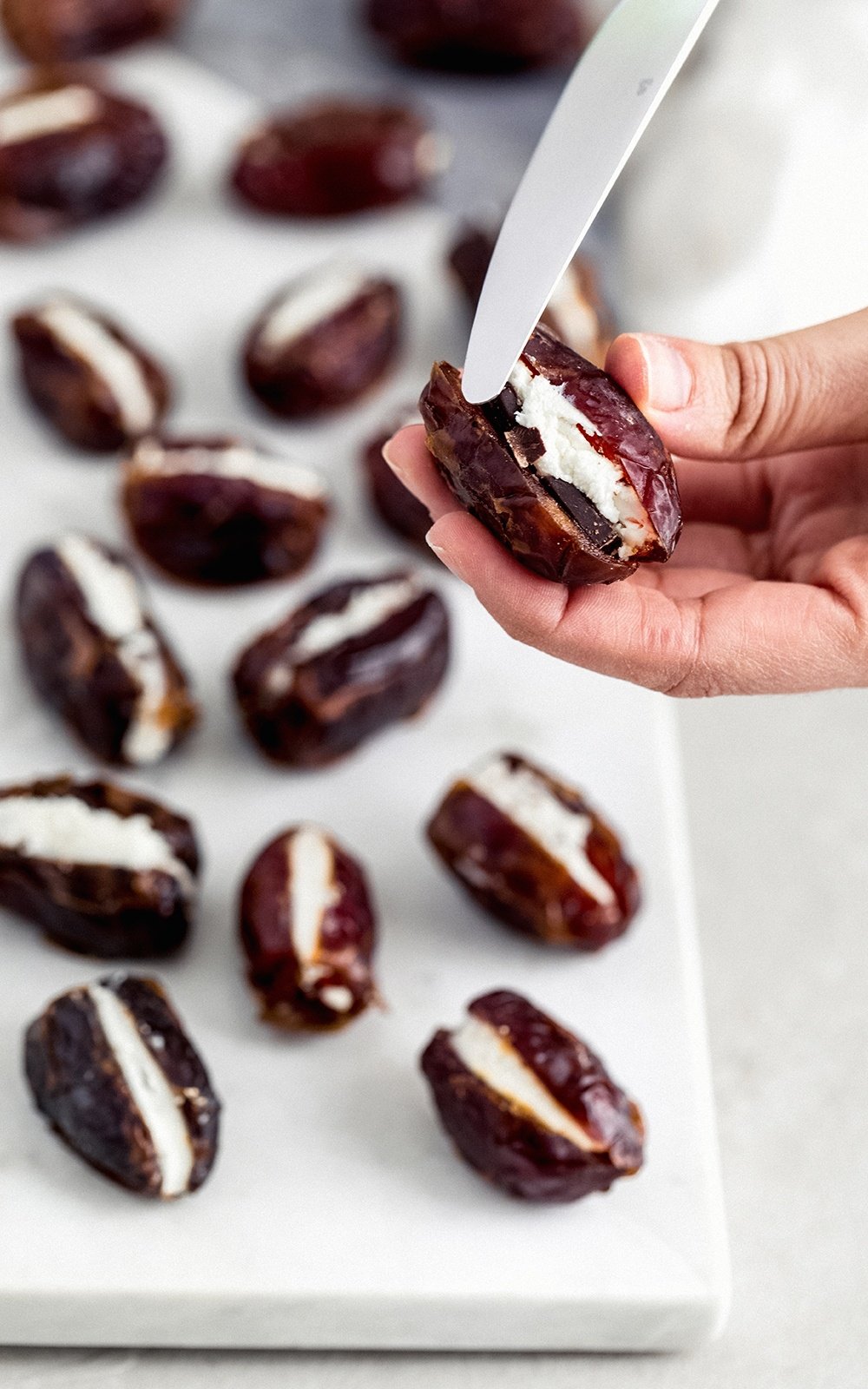 spreading goat into a stuffed date with a knife