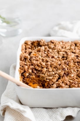 healthy sweet potato casserole in a baking dish with a wooden spoon