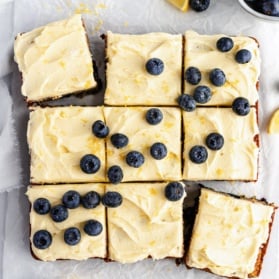 healthy lemon blueberry zucchini cake cut into nine slices topped with frosting