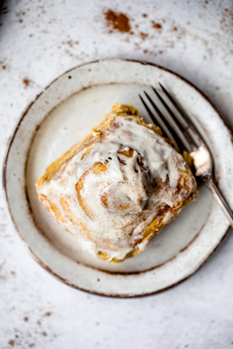 pumpkin cinnamon roll on a plate with a fork