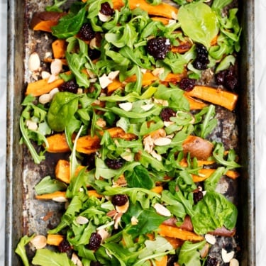 Roasted sweet potato arugula salad on a baking sheet
